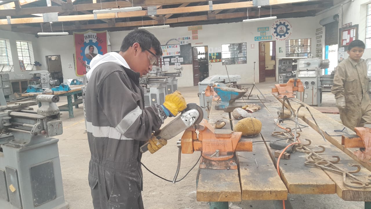 Estudiante usando herramienta el&eacute;ctrica en taller de producci&oacute;n
